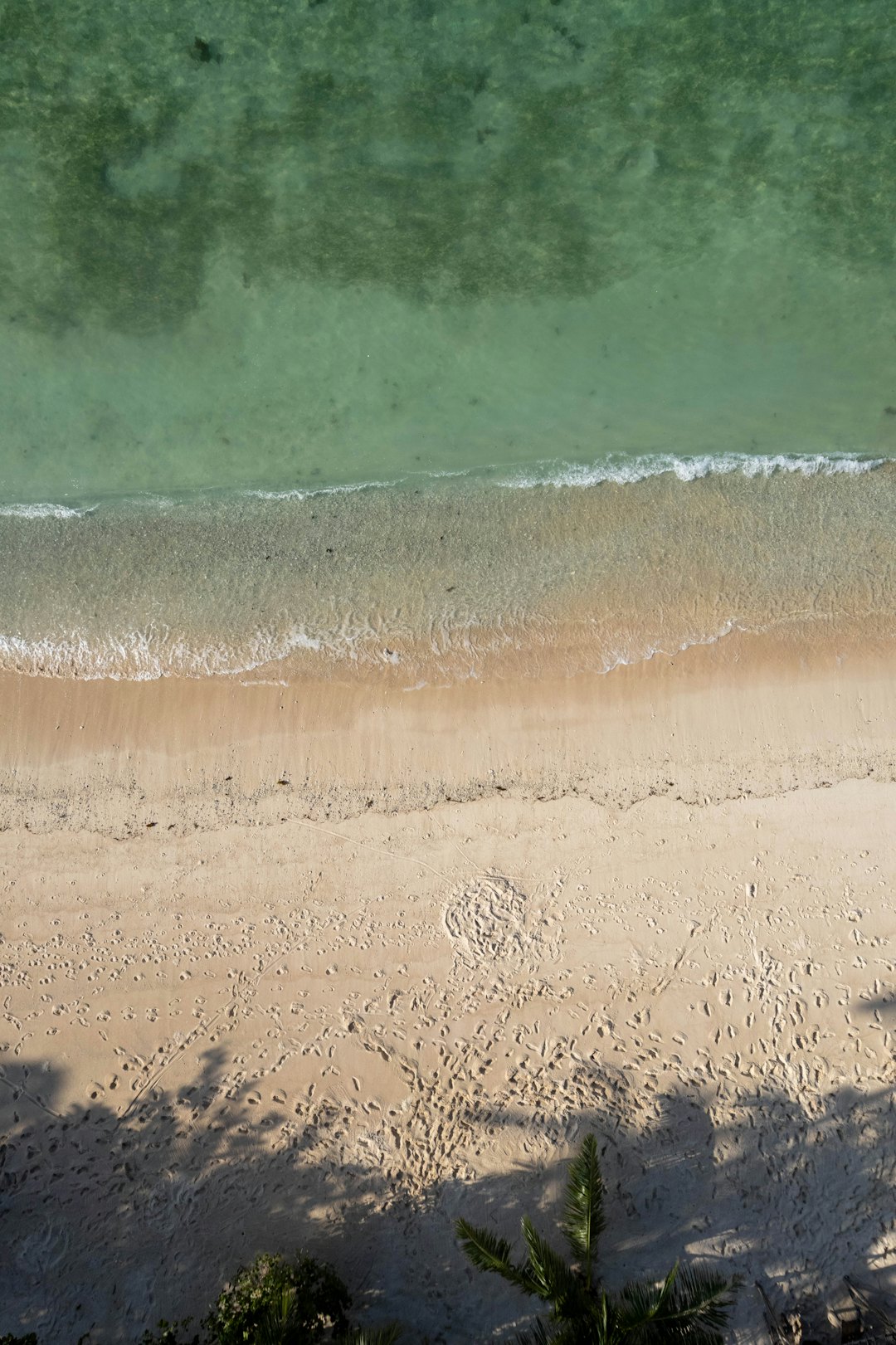 Sandstrand mit türkisfarbenem Wasser, von oben fotografiert