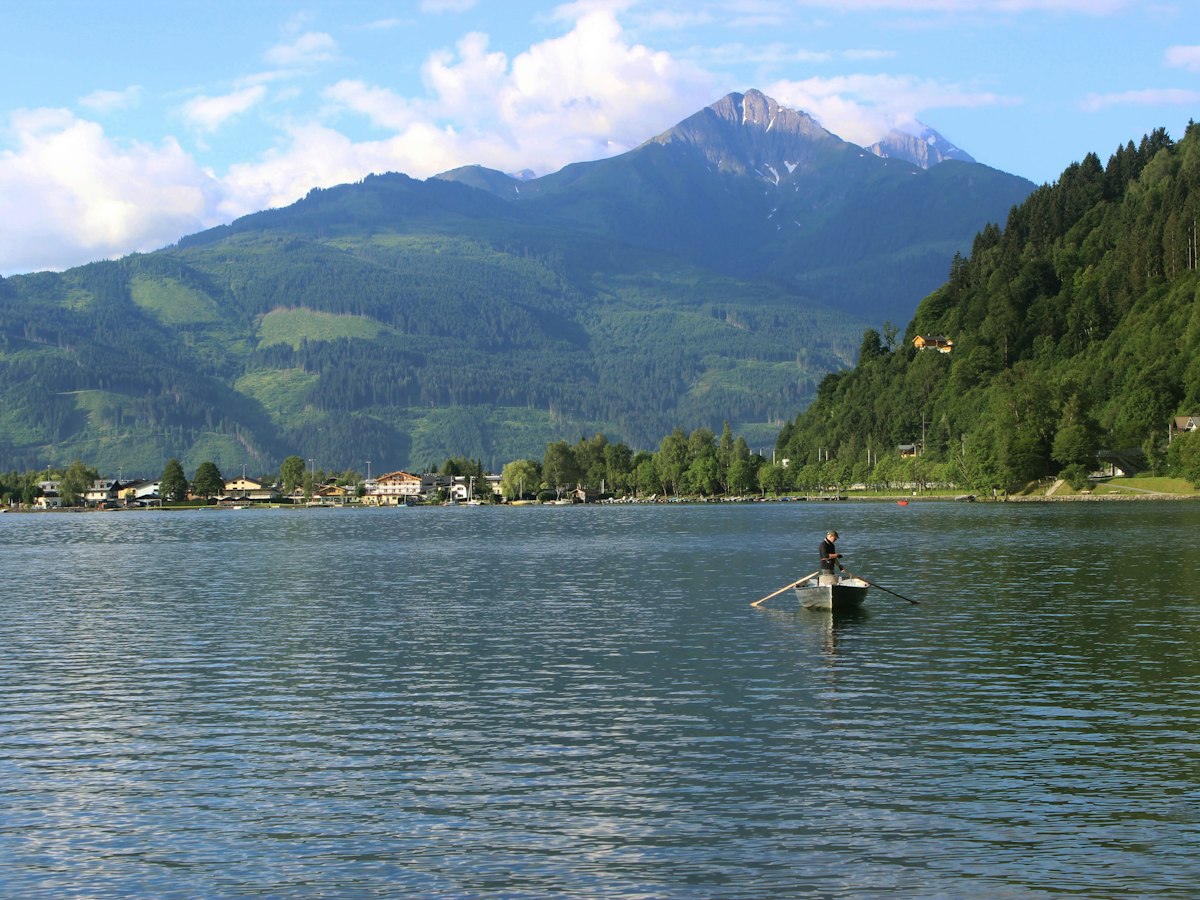 Ruderboot auf dem Zeller See im Sommer, dahinter bewaldete Berge